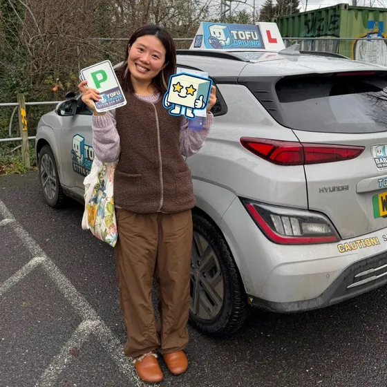 Taya - A TOFU Driving student celebrating passing the driving test next to the instructor's car