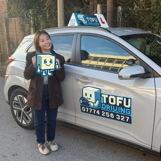 Vivian - A TOFU Driving student celebrating passing the driving test next to the instructor's car